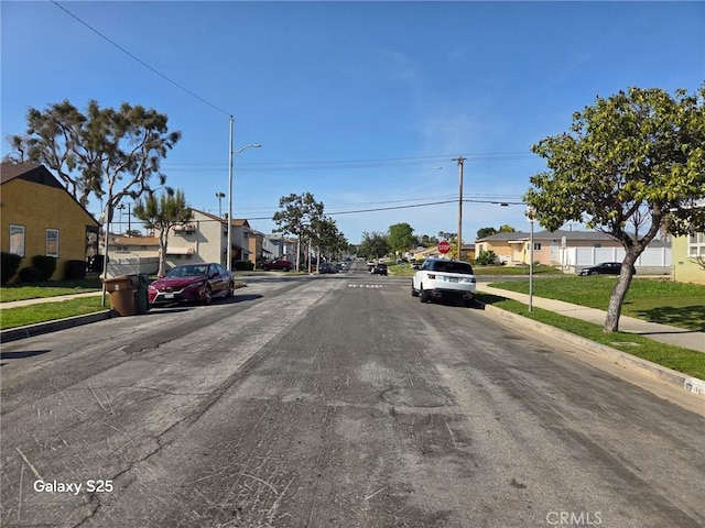 view of asphalt road with sidewalks, a residential view, street lighting, and curbs