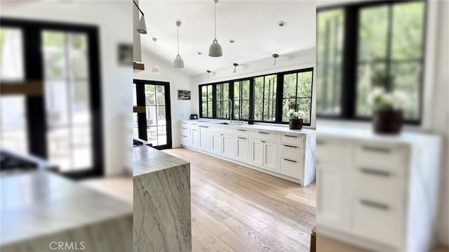 kitchen with fridge, lofted ceiling, white cabinets, light wood-style floors, and a sink