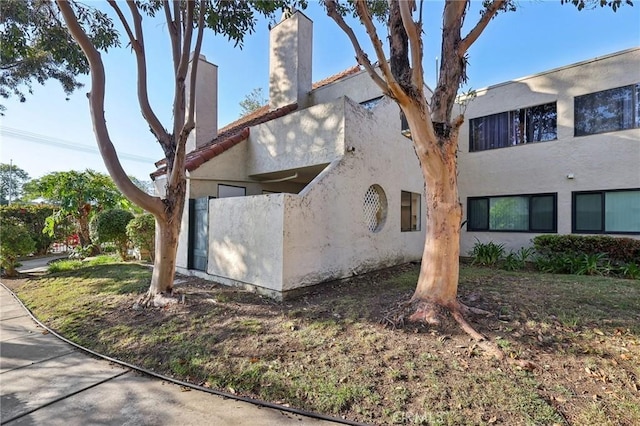 383 N Melrose Dr Unit G, Vista, CA 92083 - exterior space featuring stucco siding, a chimney, and a tiled roof