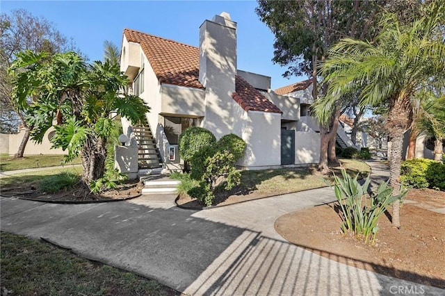 383 N Melrose Dr Unit G, Vista, CA 92083 - view of front of home featuring a tiled roof, stairway, a chimney, and stucco siding