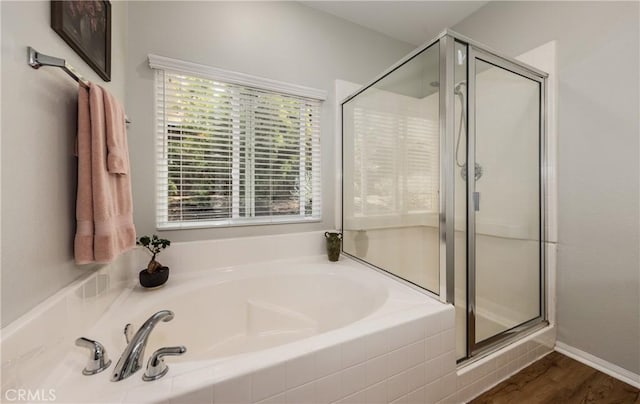 full bathroom featuring a stall shower, a bath, and wood finished floors