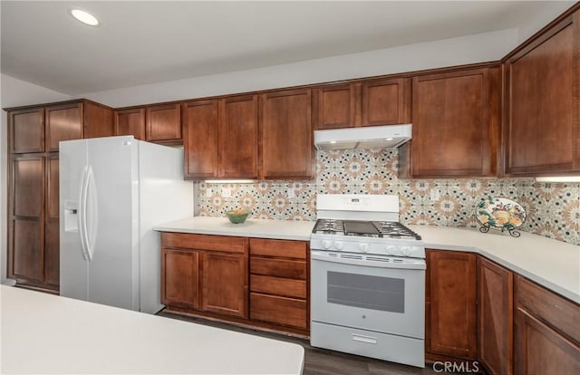 kitchen with white appliances, under cabinet range hood, light countertops, backsplash, and recessed lighting