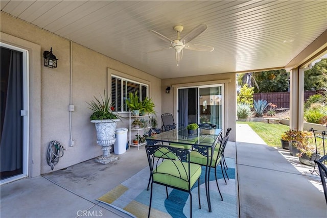 view of patio featuring outdoor dining area, fence, and a ceiling fan
