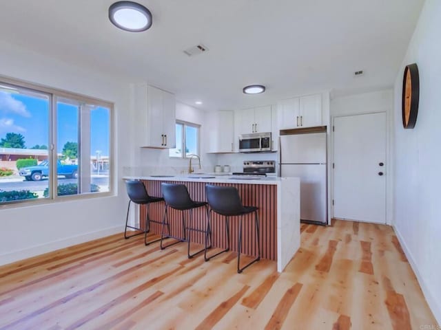 1025 Plover Way, Oceanside, CA 92057 - kitchen featuring stainless steel appliances, a peninsula, light countertops, a breakfast bar, and white cabinetry