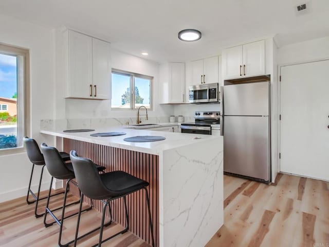 1025 Plover Way, Oceanside, CA 92057 - kitchen with appliances with stainless steel finishes, a sink, a peninsula, a breakfast bar, and light wood finished floors