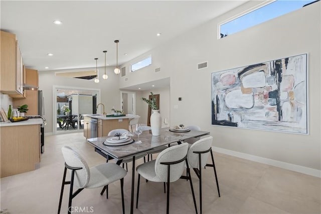 dining space with plenty of natural light, recessed lighting, baseboards, and a towering ceiling