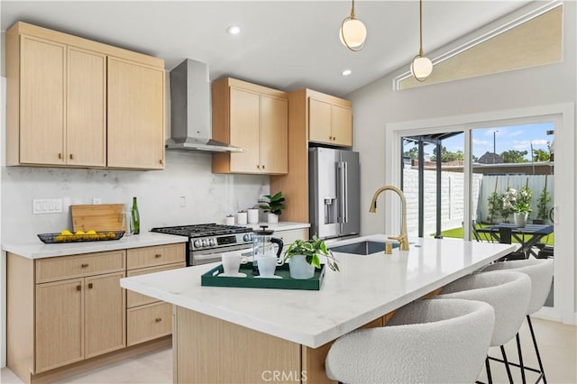 kitchen featuring wall chimney exhaust hood, light brown cabinets, a sink, stainless steel appliances, and tasteful backsplash