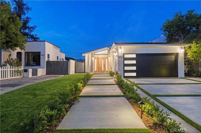 modern home with stucco siding, fence, driveway, and an attached garage