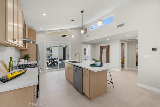 kitchen featuring a sink, appliances with stainless steel finishes, a center island with sink, light countertops, and light brown cabinets