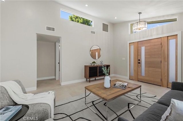 living room with a towering ceiling, a chandelier, baseboards, light carpet, and recessed lighting