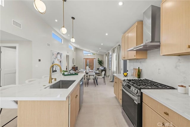 kitchen with light brown cabinets, stainless steel appliances, wall chimney exhaust hood, a sink, and recessed lighting