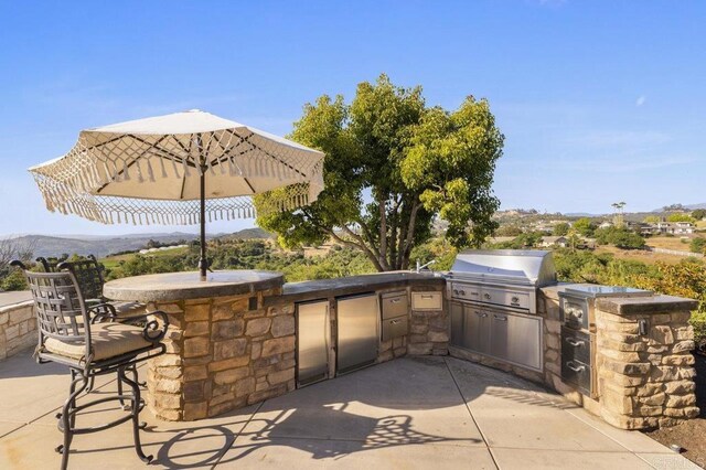 view of patio with area for grilling, exterior kitchen, exterior bar, and a mountain view
