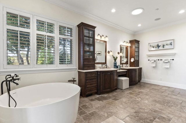 full bath with baseboards, a freestanding bath, ornamental molding, vanity, and stone tile flooring