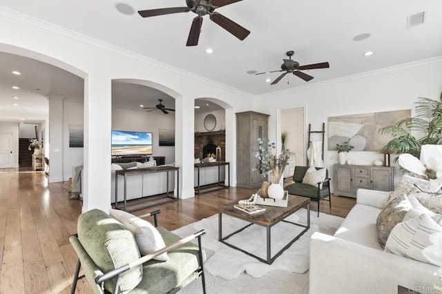 living room featuring ceiling fan, arched walkways, hardwood / wood-style floors, crown molding, and recessed lighting