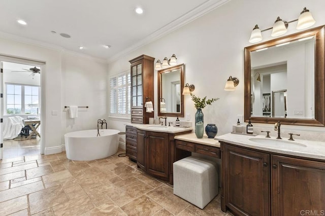 full bathroom with a freestanding tub, stone tile flooring, two vanities, crown molding, and recessed lighting