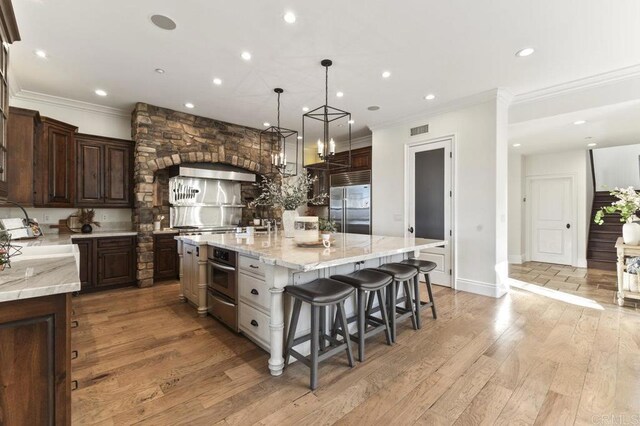 kitchen with stainless steel appliances, crown molding, recessed lighting, a kitchen bar, and a large island
