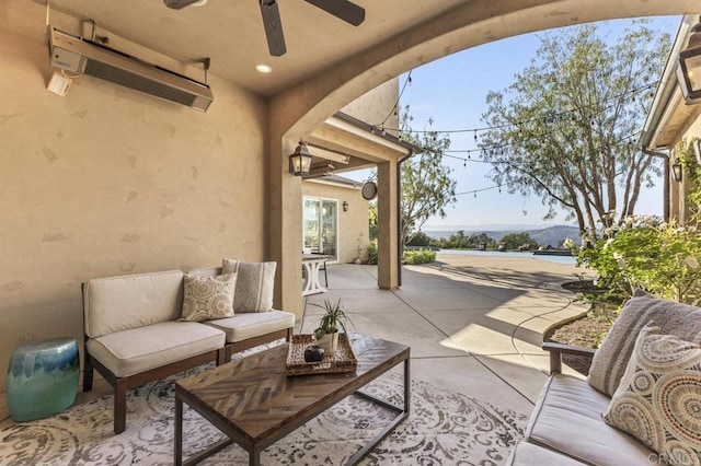 view of patio / terrace with ceiling fan, an outdoor living space, and a wall mounted air conditioner