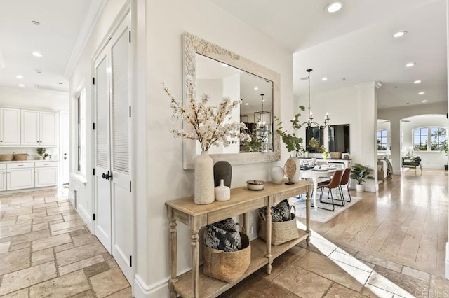 hall featuring ornamental molding, recessed lighting, stone tile floors, arched walkways, and baseboards