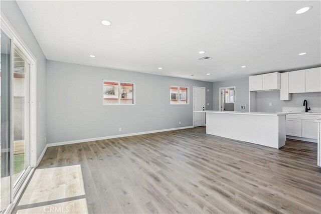 43820 Beech Ave, Lancaster, CA 93534 - unfurnished living room with light wood-style flooring, recessed lighting, baseboards, and a sink