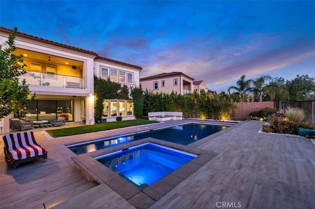 pool at dusk featuring an in-ground hot tub, a patio, an outdoor living space, and a fenced backyard