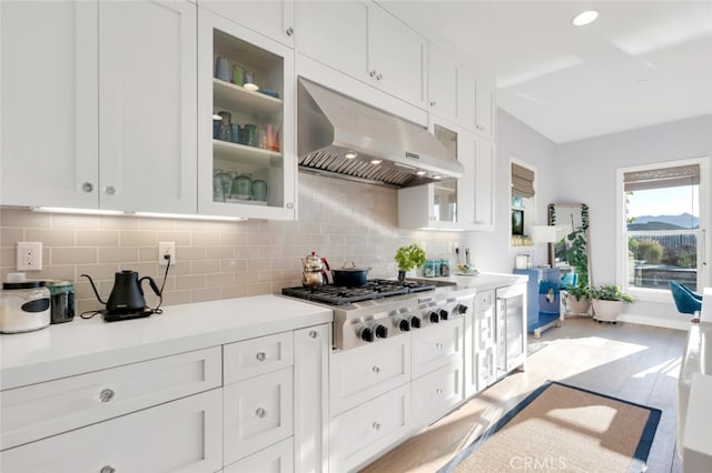 kitchen featuring under cabinet range hood, stainless steel gas cooktop, decorative backsplash, and white cabinets