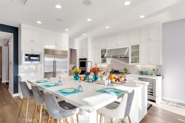 kitchen with built in appliances, beverage cooler, white cabinets, and recessed lighting