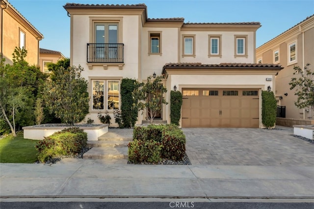 mediterranean / spanish house featuring a balcony, stucco siding, and driveway