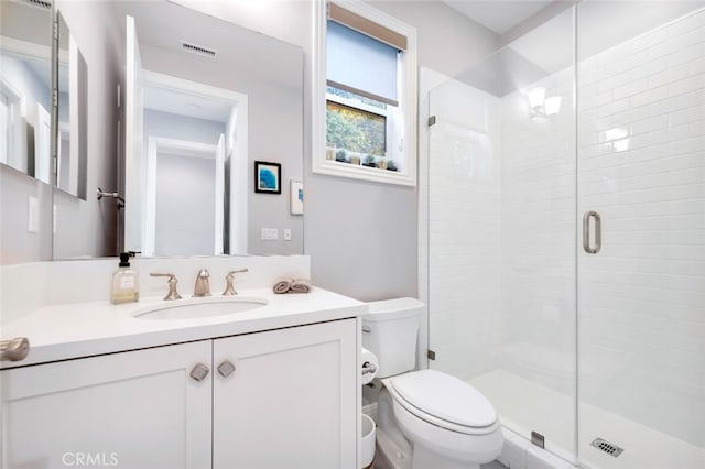 bathroom with a stall shower, toilet, and vanity
