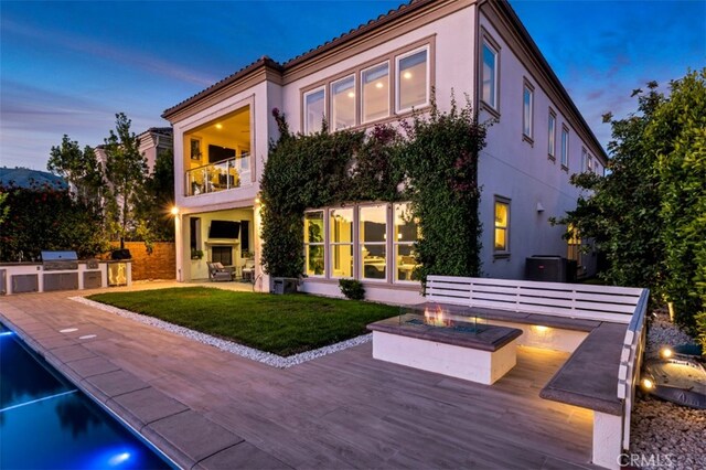 back of property featuring an outdoor fire pit, area for grilling, stucco siding, and a balcony