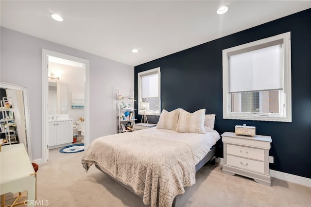 bedroom with light colored carpet, baseboards, recessed lighting, and connected bathroom