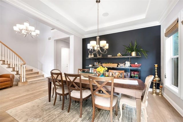 dining room with a chandelier, stairway, wood finished floors, a tray ceiling, and baseboards