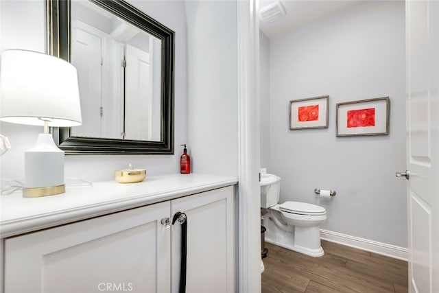 bathroom featuring toilet, wood finished floors, baseboards, and vanity