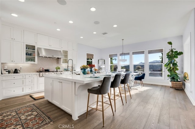 kitchen with exhaust hood, light wood finished floors, light countertops, recessed lighting, and white cabinetry