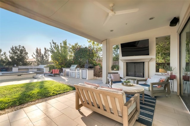 view of patio / terrace with an outdoor kitchen, an outdoor living space with a fireplace, area for grilling, ceiling fan, and fence