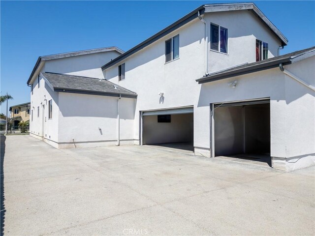 back of house featuring stucco siding, a garage, and concrete driveway