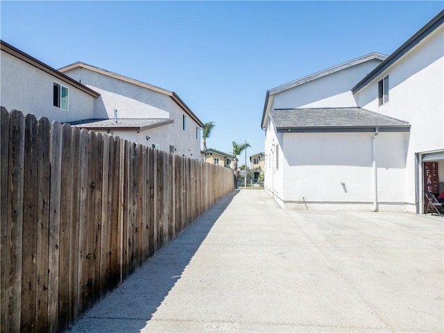 view of side of home with stucco siding, fence, and a patio area
