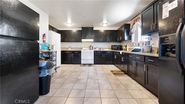 kitchen featuring black appliances, light countertops, light tile patterned floors, a sink, and under cabinet range hood