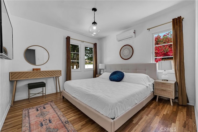 bedroom featuring a wall mounted AC, wood finished floors, and baseboards