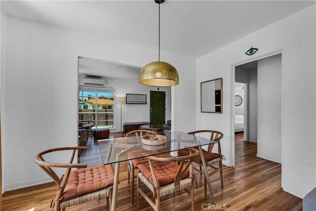 dining room with an AC wall unit, wood finished floors, and baseboards