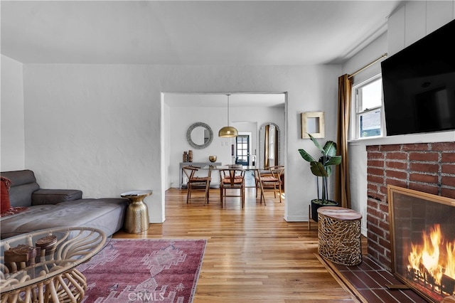living room with a brick fireplace, plenty of natural light, and light wood finished floors