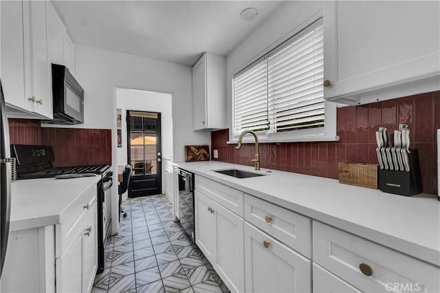 kitchen featuring black appliances, a sink, light countertops, and white cabinetry