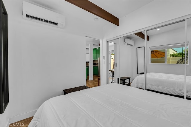 bedroom featuring a wall mounted air conditioner, beamed ceiling, wood finished floors, a closet, and recessed lighting