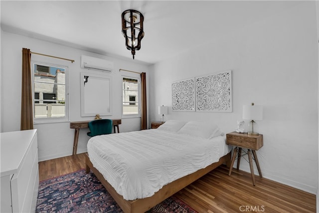 bedroom featuring an AC wall unit, wood finished floors, and baseboards