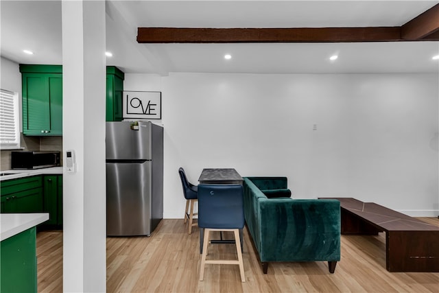 kitchen with green cabinets, freestanding refrigerator, light countertops, light wood finished floors, and recessed lighting