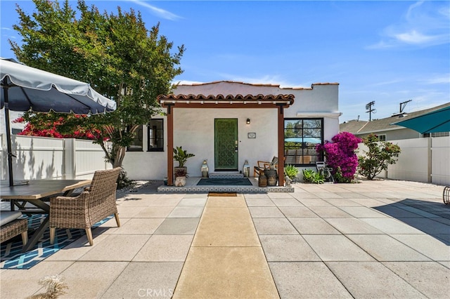 rear view of house featuring a patio area, stucco siding, and a tiled roof