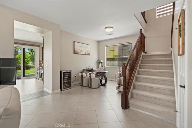 stairway with beverage cooler, plenty of natural light, baseboards, and tile patterned flooring