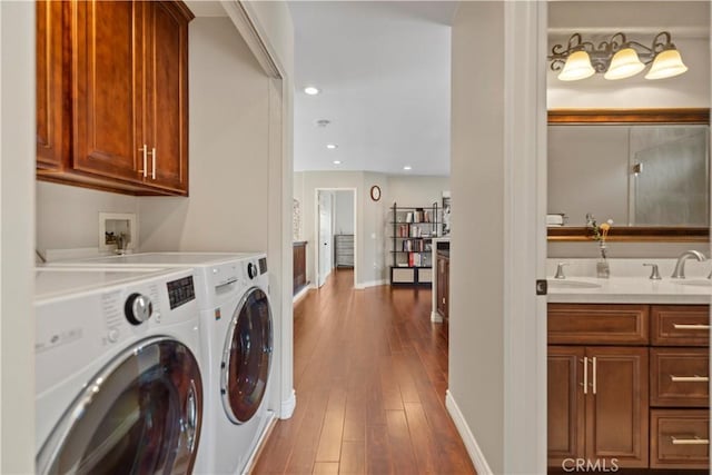 clothes washing area featuring washing machine and clothes dryer, hardwood / wood-style flooring, baseboards, and recessed lighting