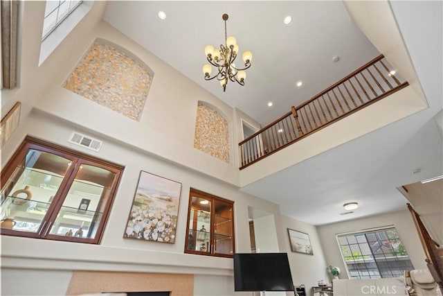 living room featuring a towering ceiling, a chandelier, and recessed lighting