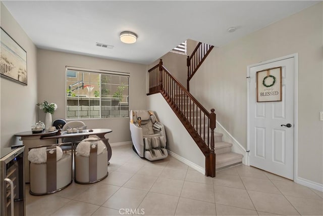 entryway featuring wine cooler, stairway, light tile patterned floors, and baseboards