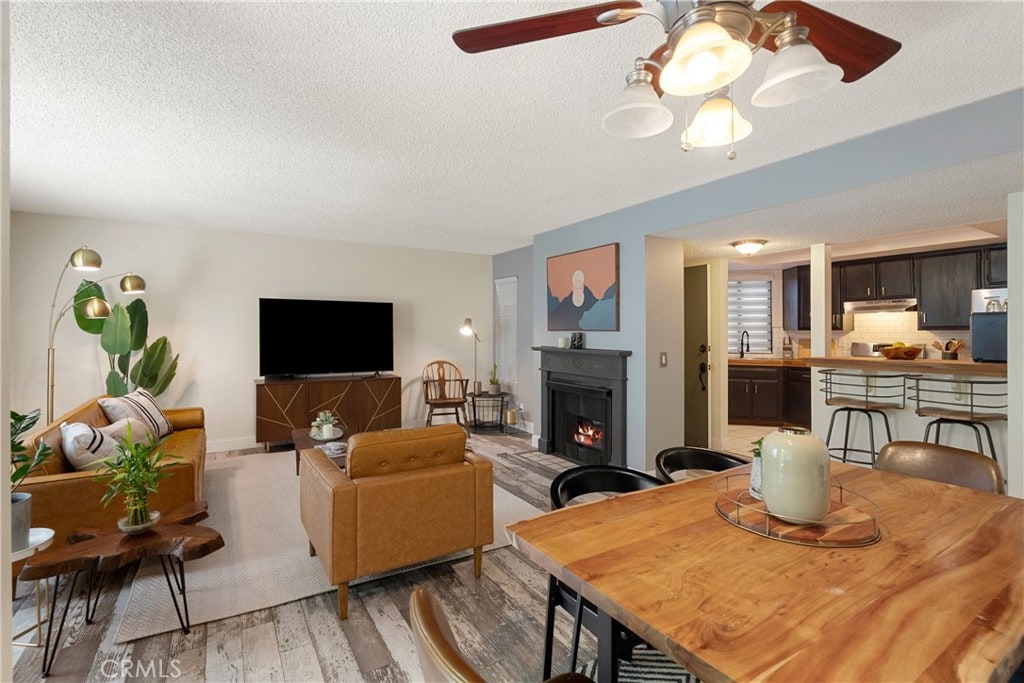 645 Pacific Ave Unit 304, Long Beach, CA 90802 - living area featuring light wood-style flooring, a textured ceiling, a lit fireplace, and ceiling fan